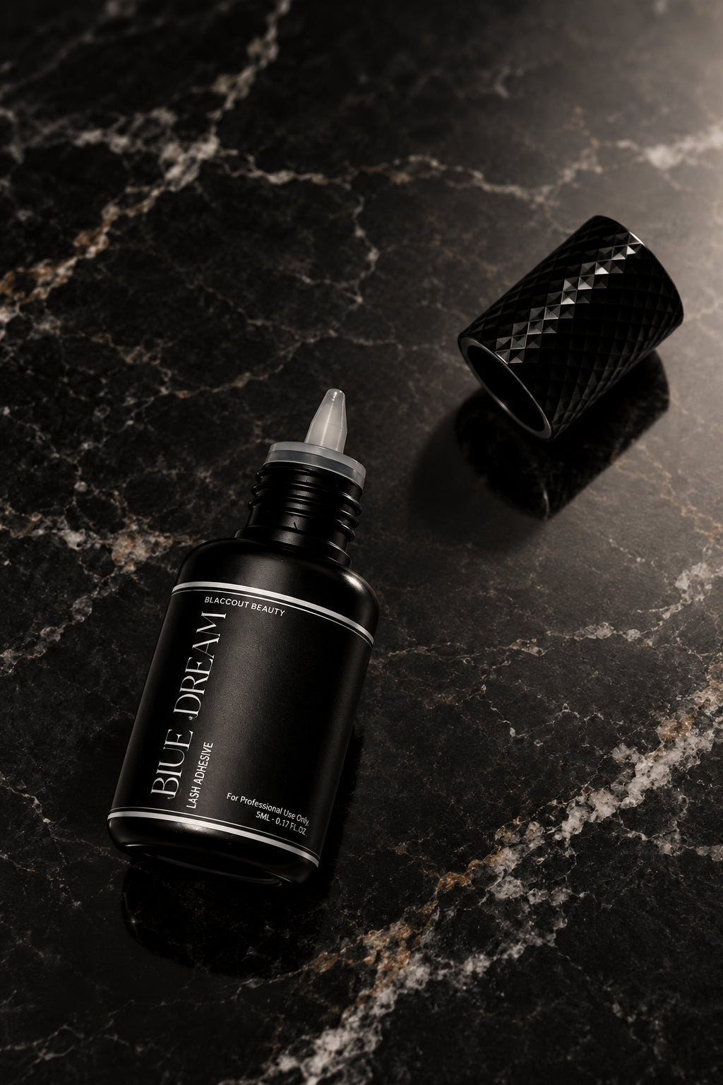 A small black bottle with a pointed applicator tip and a separate textured black cap, photographed on a plain light background. The bottle label reads 'BLUE DREAM'.